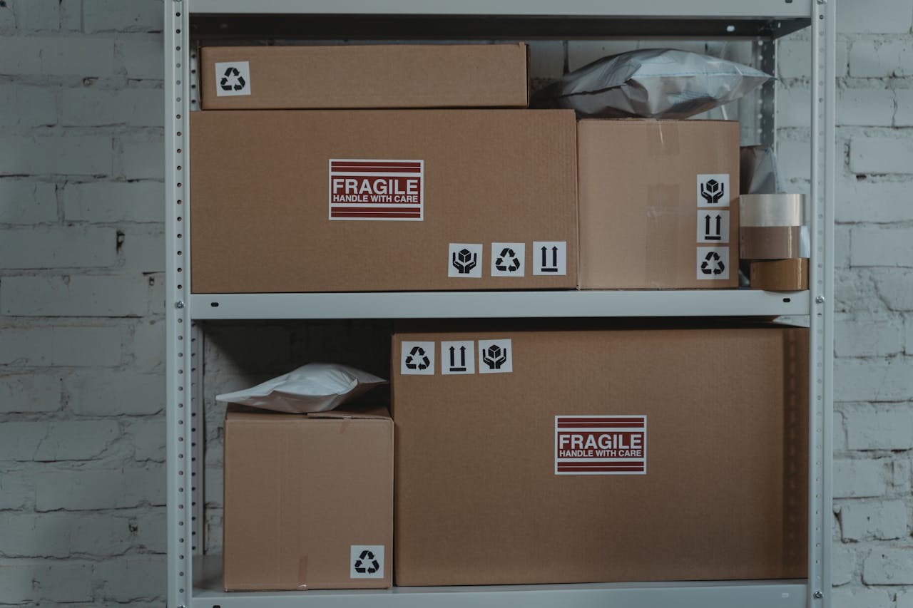 Cardboard boxes labeled Fragile stacked on metal shelving in a storage room.